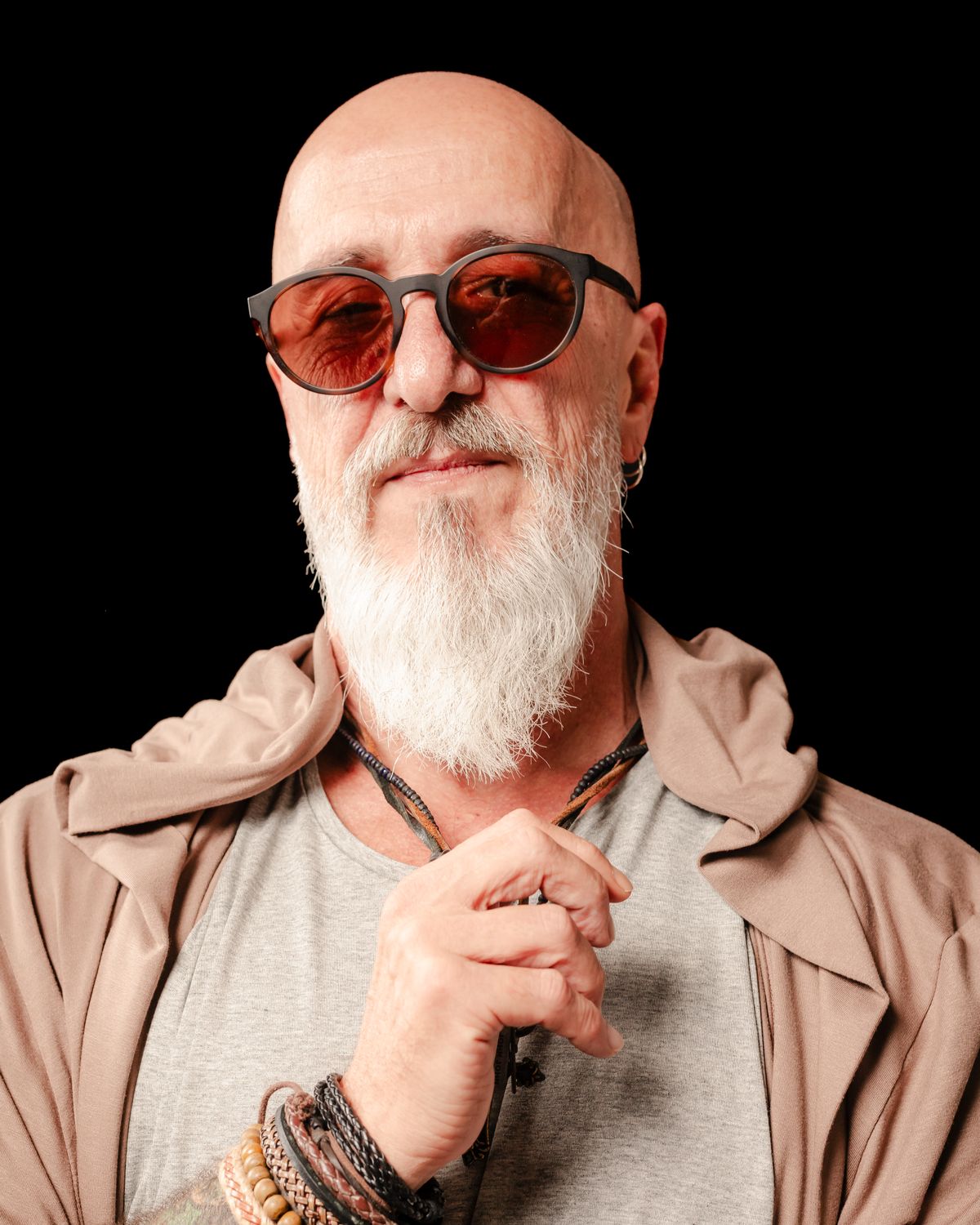 Retrato de NeoClassic, de óculos escuros e barba branca, com a mão junto ao peito