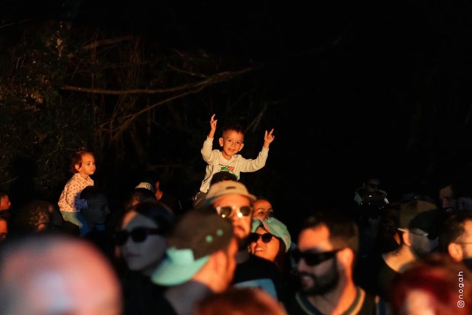 Criança sorrindo nos ombros de um adulto no parque, na luz do fim da tarde
